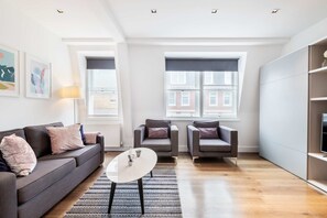 Uma sala de estar moderna com um sofá, duas poltronas, uma mesa de centro e um rack para TV.
