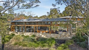 A modern house with a large glass facade, stone foundation, and a patio area.