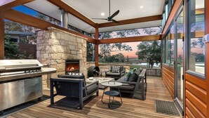An outdoor patio with a stone fireplace, a grill, and a seating area with a view of the landscape. - HUNTER VILLA - THE VINTAGE (POKOLBIN)