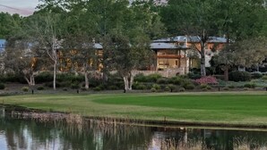 A large, multi-story house with a well-maintained lawn and a pond in the foreground. - HUNTER VILLA - THE VINTAGE (POKOLBIN)