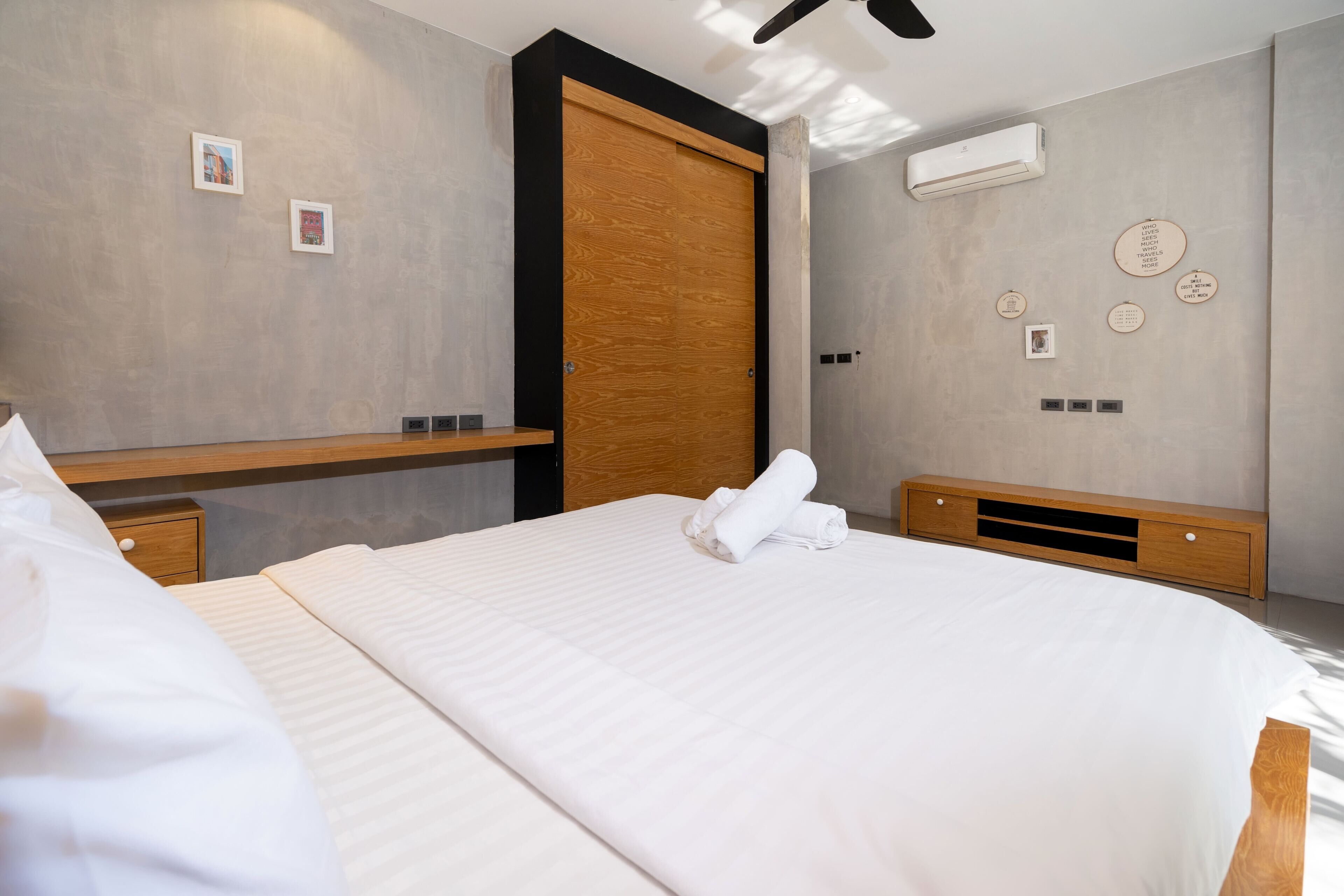 A modern hotel room with a large bed, a wooden wardrobe, a built-in shelf, and a wall with decorative plates.