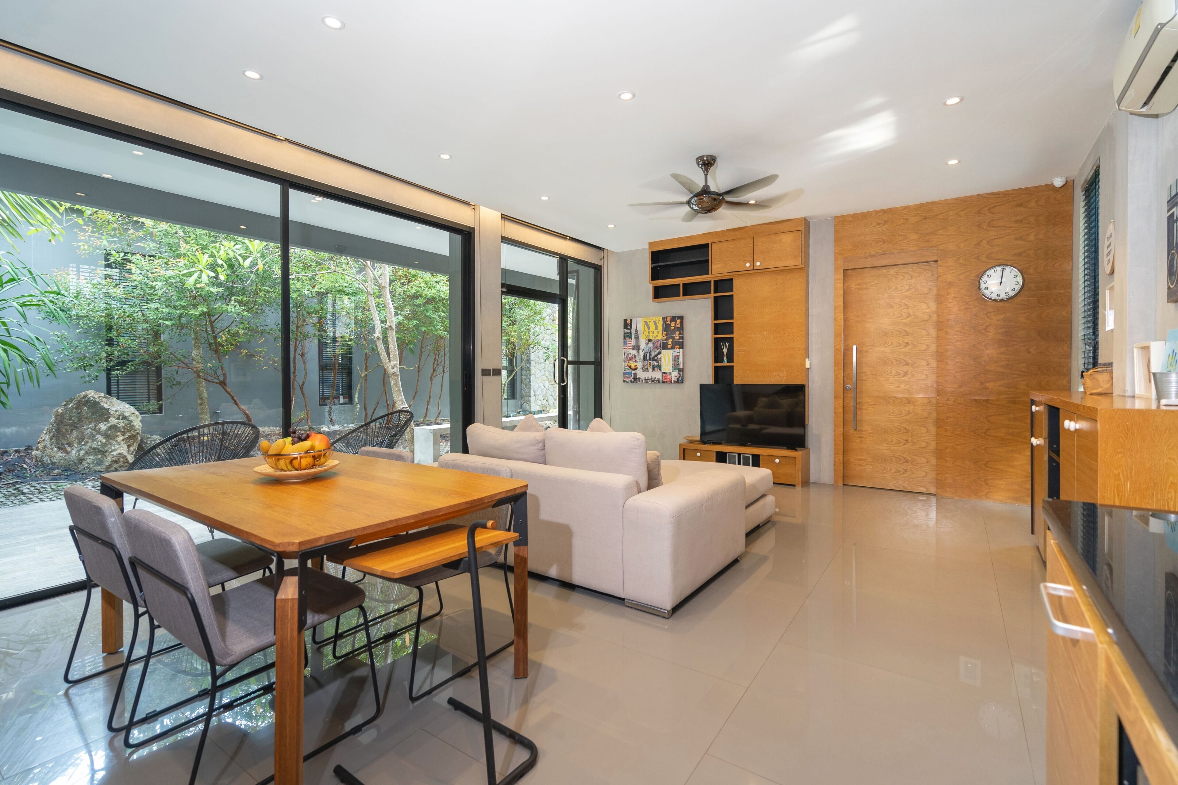 A modern living space with a dining area, sofa, and kitchen.