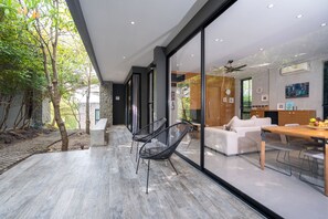 Un interior moderno con comedor, sofá y un amplio ventanal con vistas a un jardín.