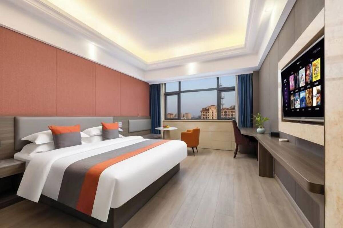 A modern hotel room with a large bed, a desk, and a TV mounted on the wall.