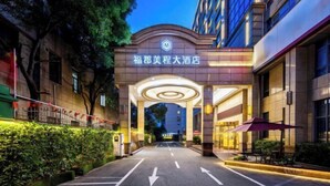 A hotel entrance with a modern design, featuring a prominent archway and a well-lit pathway leading to the building. - Fujun Meicheng Hotel (Suzhou)