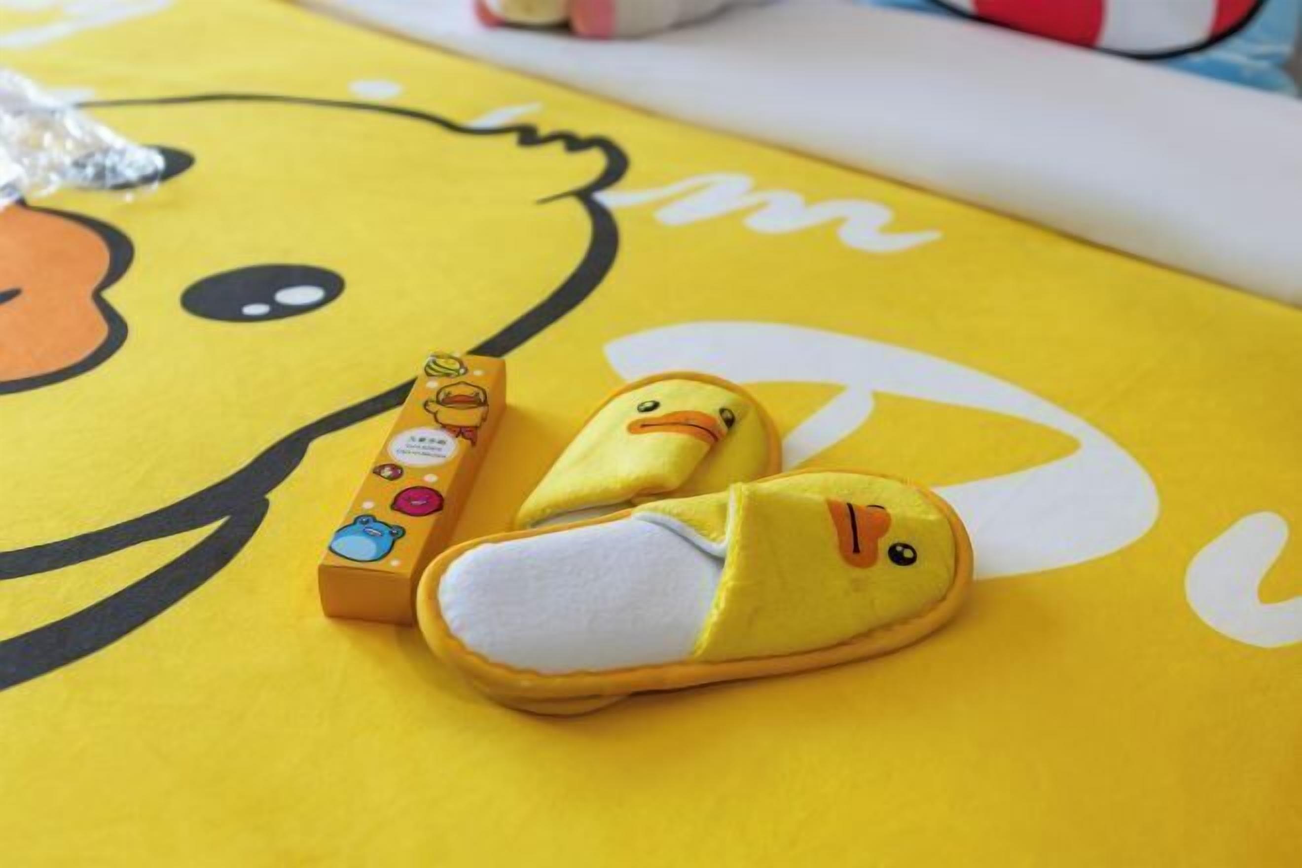 Une paire de pantoufles jaunes ornées d’un motif de canard sur une surface jaune.