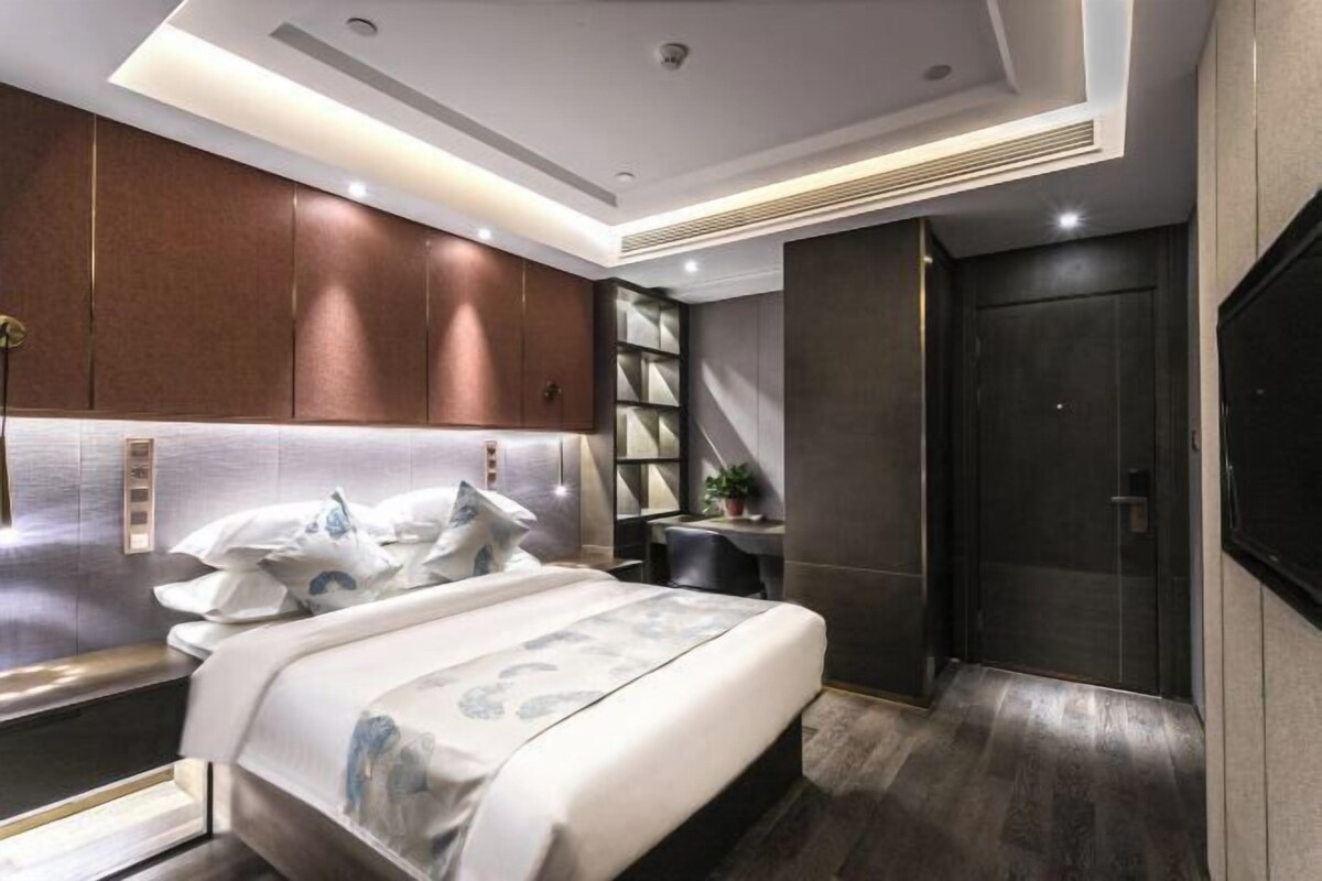 A modern bedroom with a large bed, a desk, and a wardrobe.