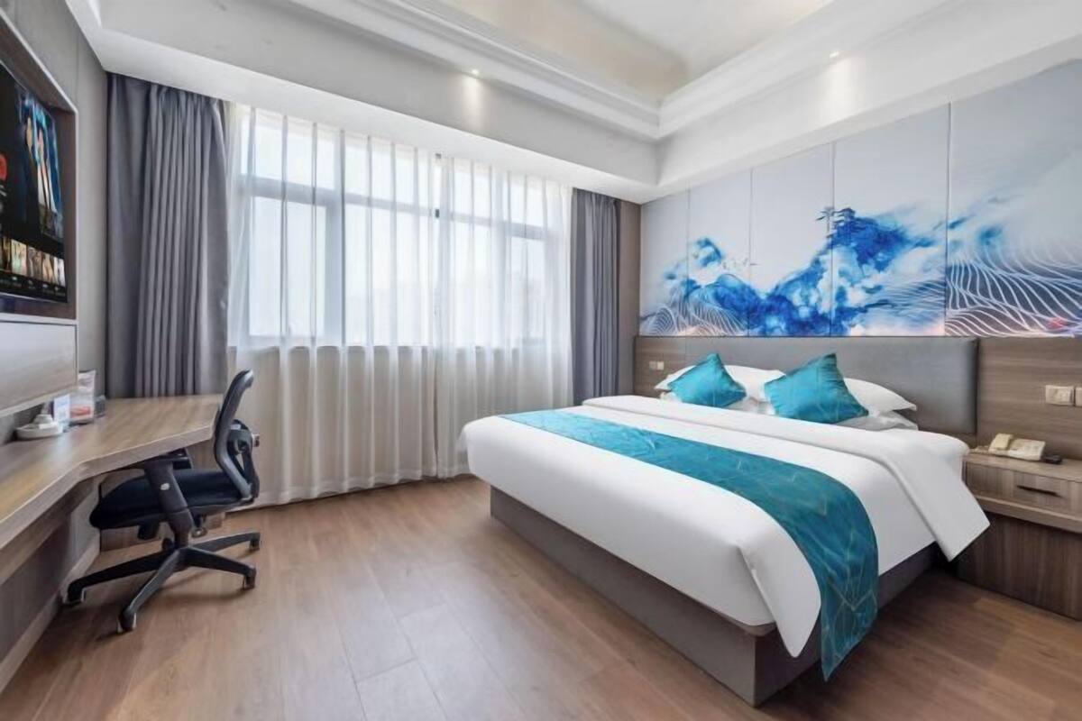 A modern hotel room with a large bed, a desk, and a TV.