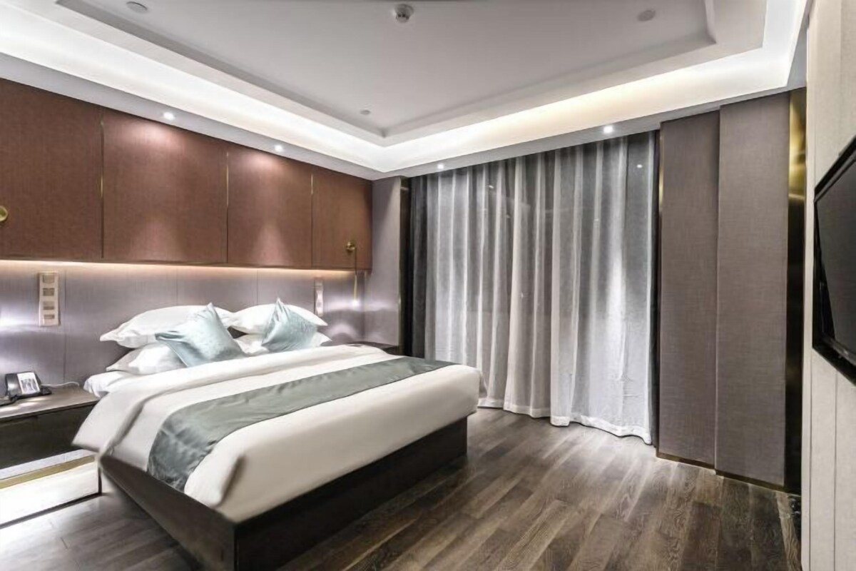 A modern bedroom with a large bed, wooden headboard, and a flat-screen TV.
