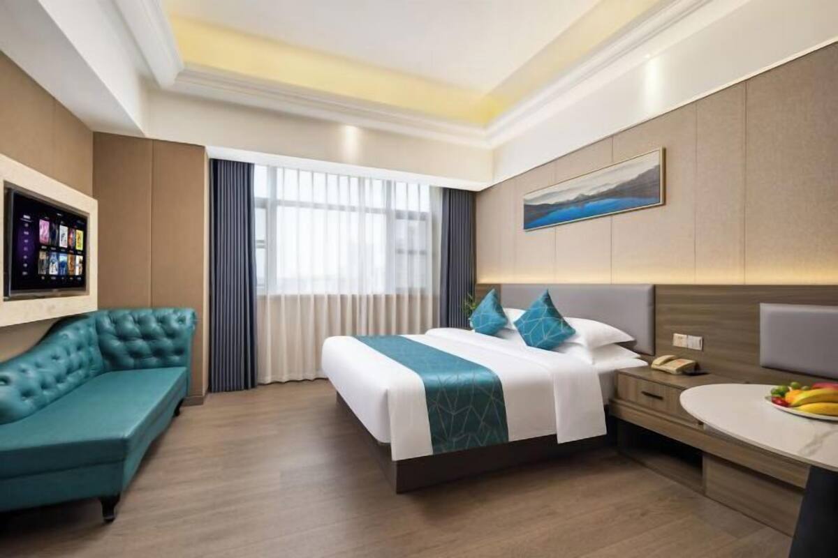 A hotel room with a bed, a sofa, a desk, and a TV.
