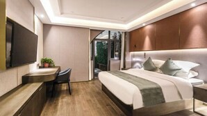 A modern bedroom with a large bed, a desk, and a TV. - Fujun Meicheng Hotel (Suzhou)