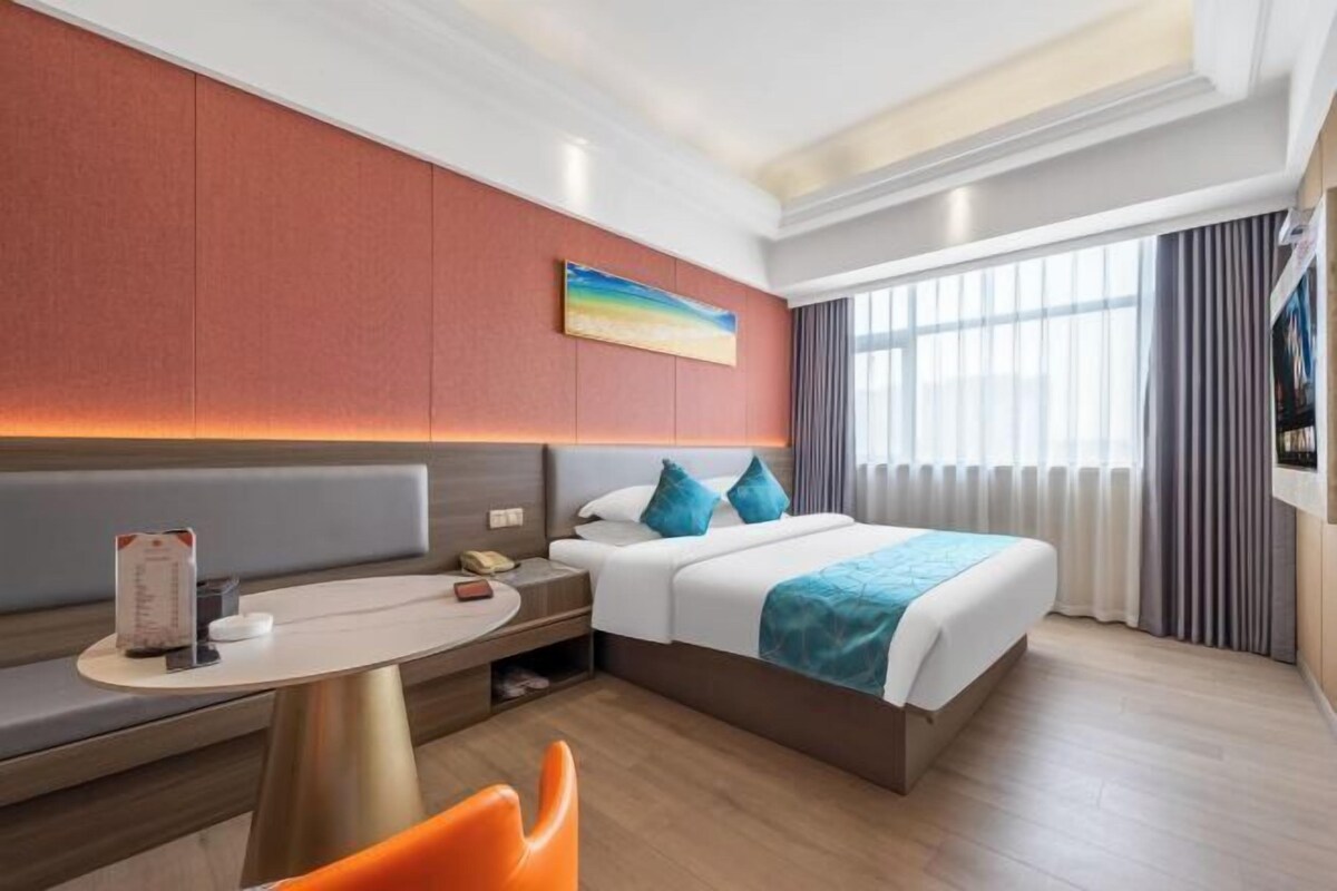 A modern hotel room with a bed, a desk, and a seating area.