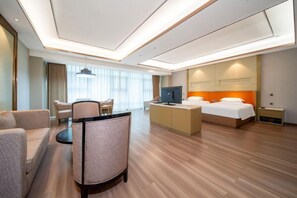 Habitación de hotel con cama, escritorio, televisión y zona de estar.