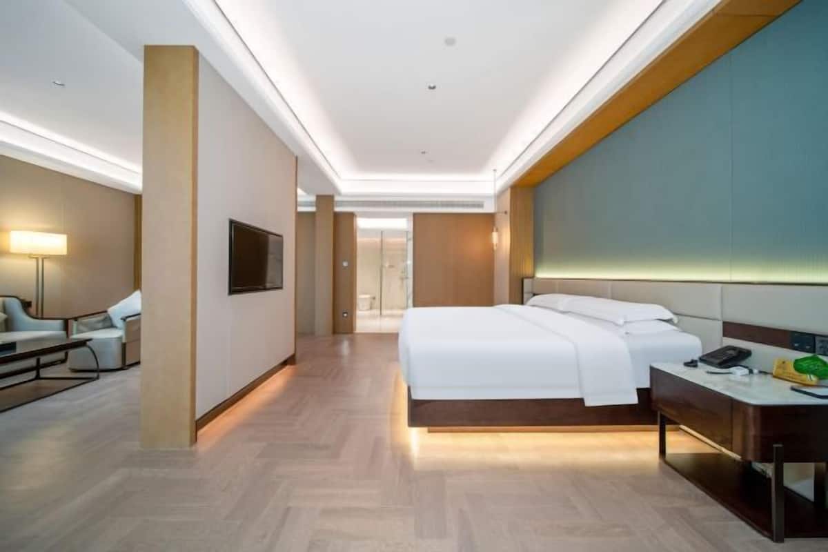 A modern hotel room with a bed, desk, and seating area.