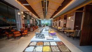 Zona de bufé con diferentes opciones de comida y un área de estar con mesas y sillas.