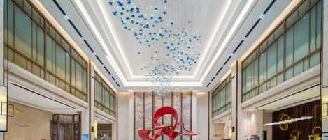 A spacious lobby with a high ceiling, a central red sculpture, and a reception desk.