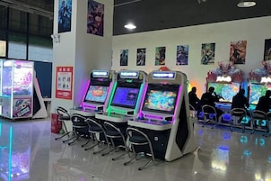 Una hilera de máquinas de videojuegos de arcade con múltiples pantallas y sillas al frente.