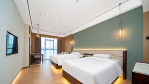 Habitación de hotel con dos camas, un escritorio y vista a la ciudad.