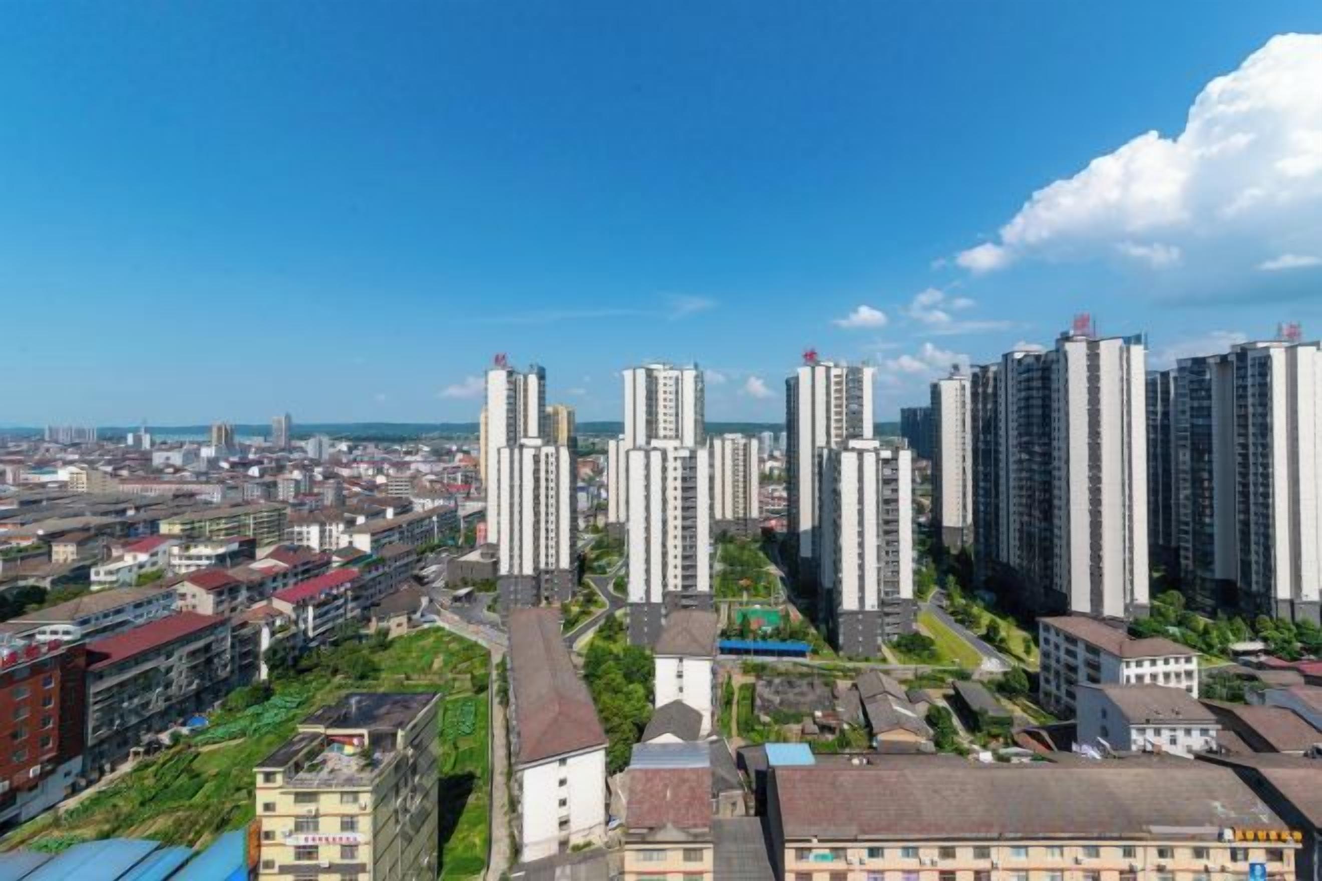 Zona residencial de gran altura con varios edificios de apartamentos, cielo despejado y una vista distante de una masa de agua.