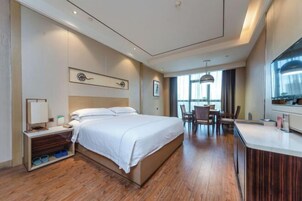 Una habitación de hotel moderna con una cama grande, un escritorio y un área de comedor.