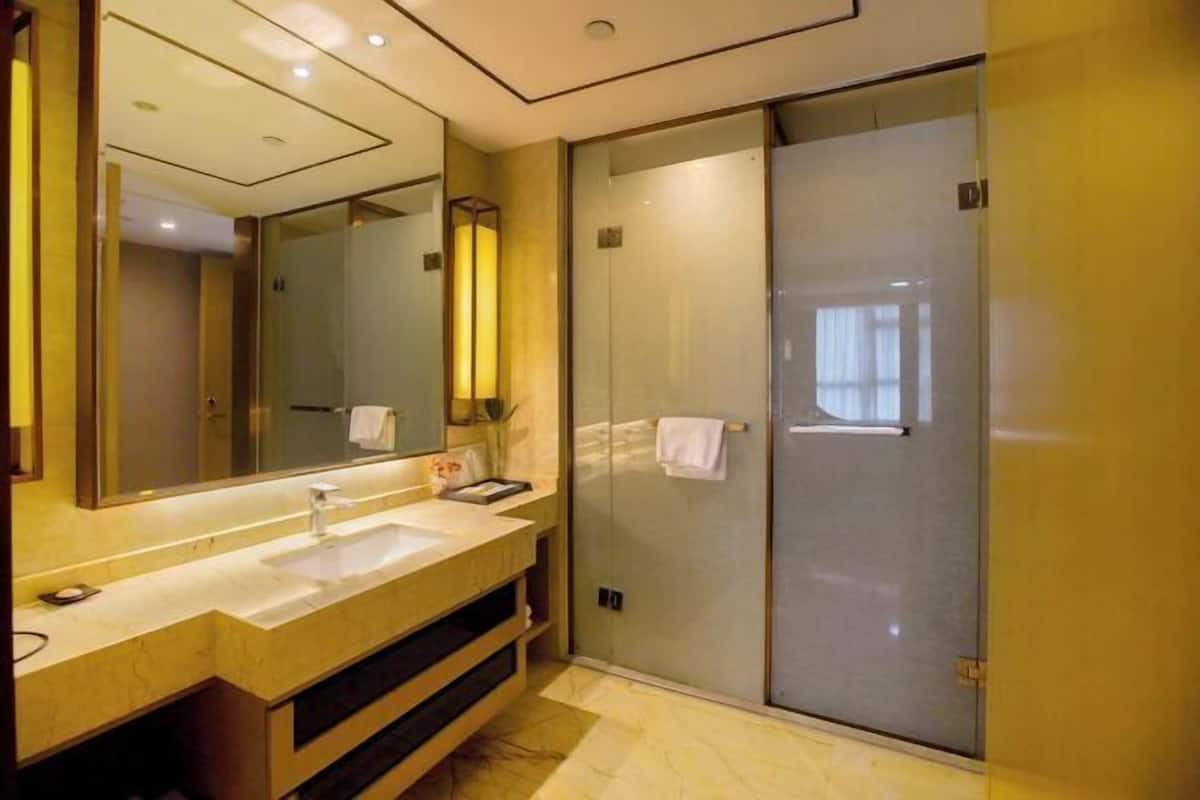 A modern bathroom with a large mirror, two sinks, a shower enclosure, and a vanity.