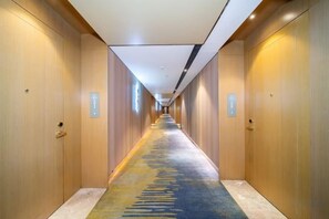 Un pasillo de hotel con puertas de madera, piso alfombrado y una larga extensión.