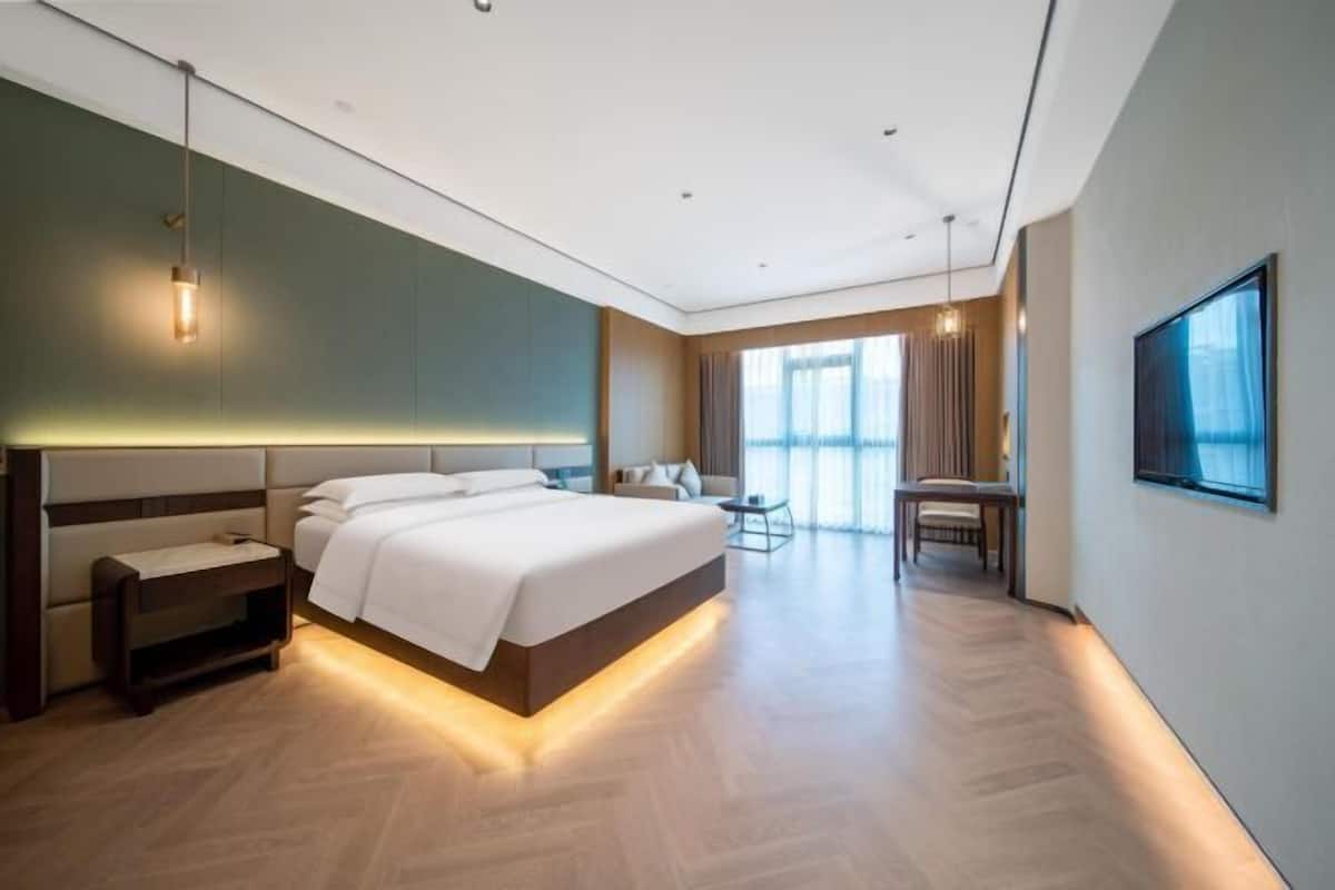 A modern hotel room with a large bed, bedside tables, a desk, and a chair.
