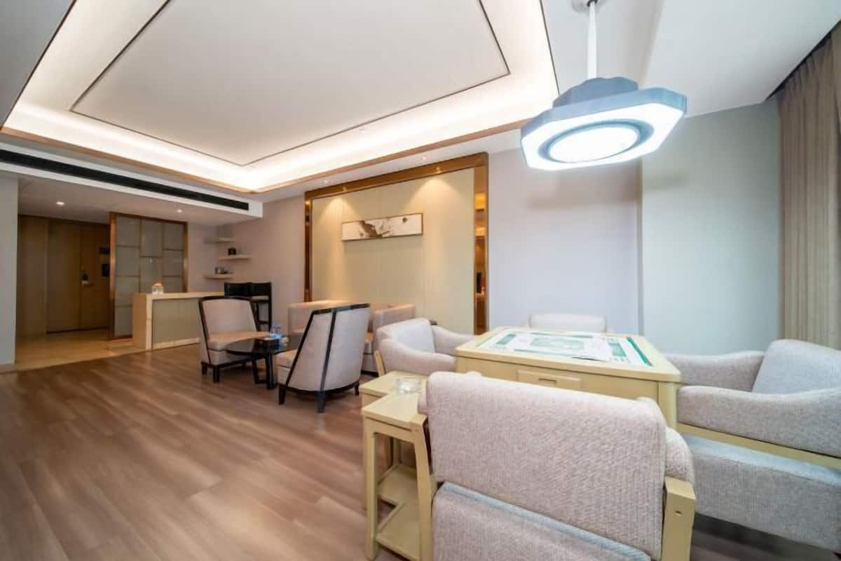 A modern hotel room with a wooden floor, a seating area with a table, and a large mirror.