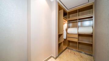 Un vestidor amplio con estantes y espacio para colgar ropa, suelo de mármol y una lámpara sobre él.