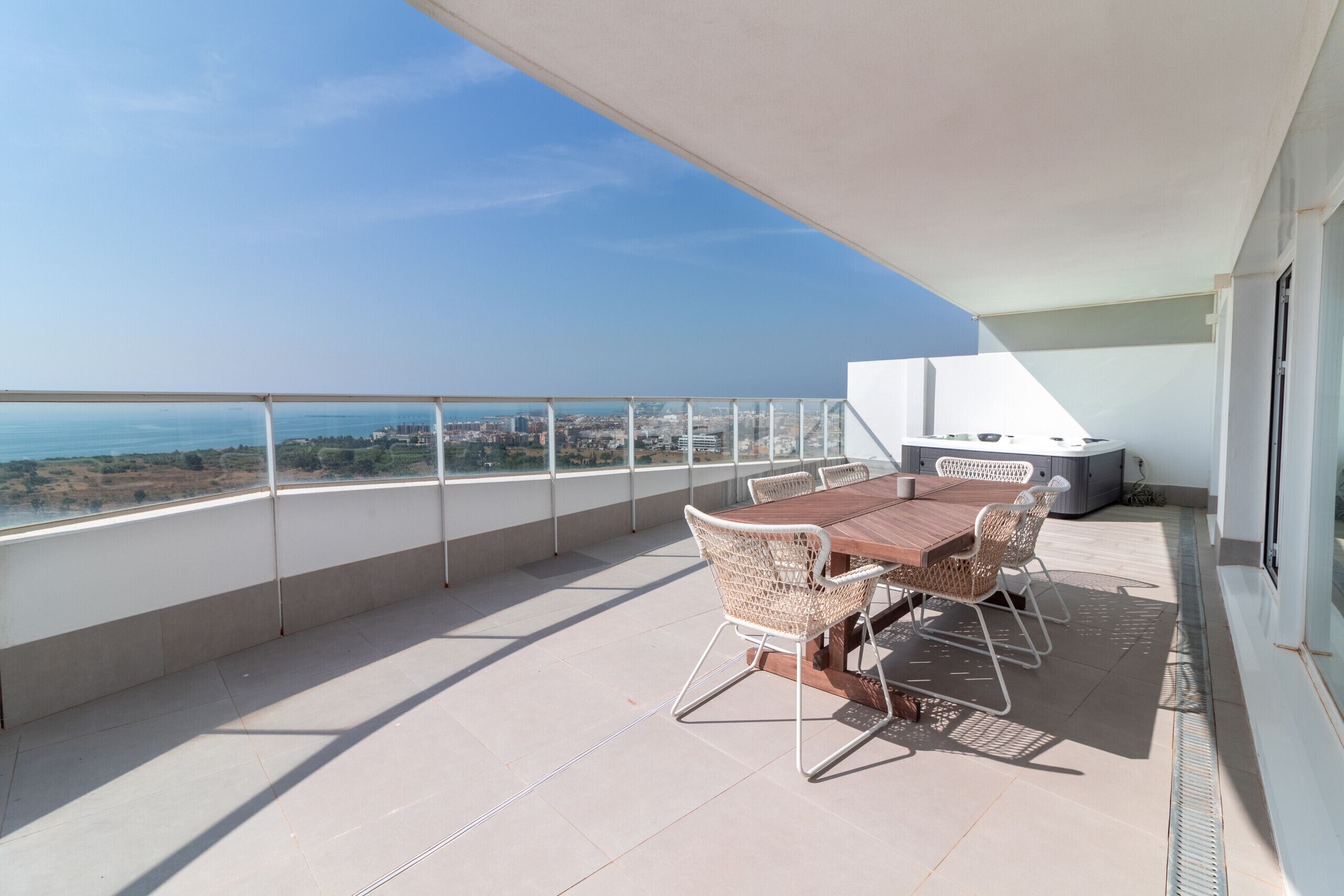A balcony with a table and chairs, a grill, and a view of the city.