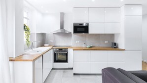 A modern kitchen with white cabinetry, a wooden countertop, a built-in oven, and a microwave.