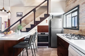 A modern kitchen with a central island, built-in oven, refrigerator, and gas stove.