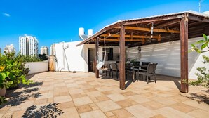 Un patio exterior con una pérgola de madera, una mesa de comedor y sillas.