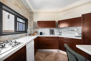 A modern kitchen with a gas stove, white countertops, wooden cabinets, and a chalkboard menu.