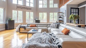 Ein geräumiges Wohnzimmer mit einer großen Eckcouch, einem Couchtisch und einem Kamin.
