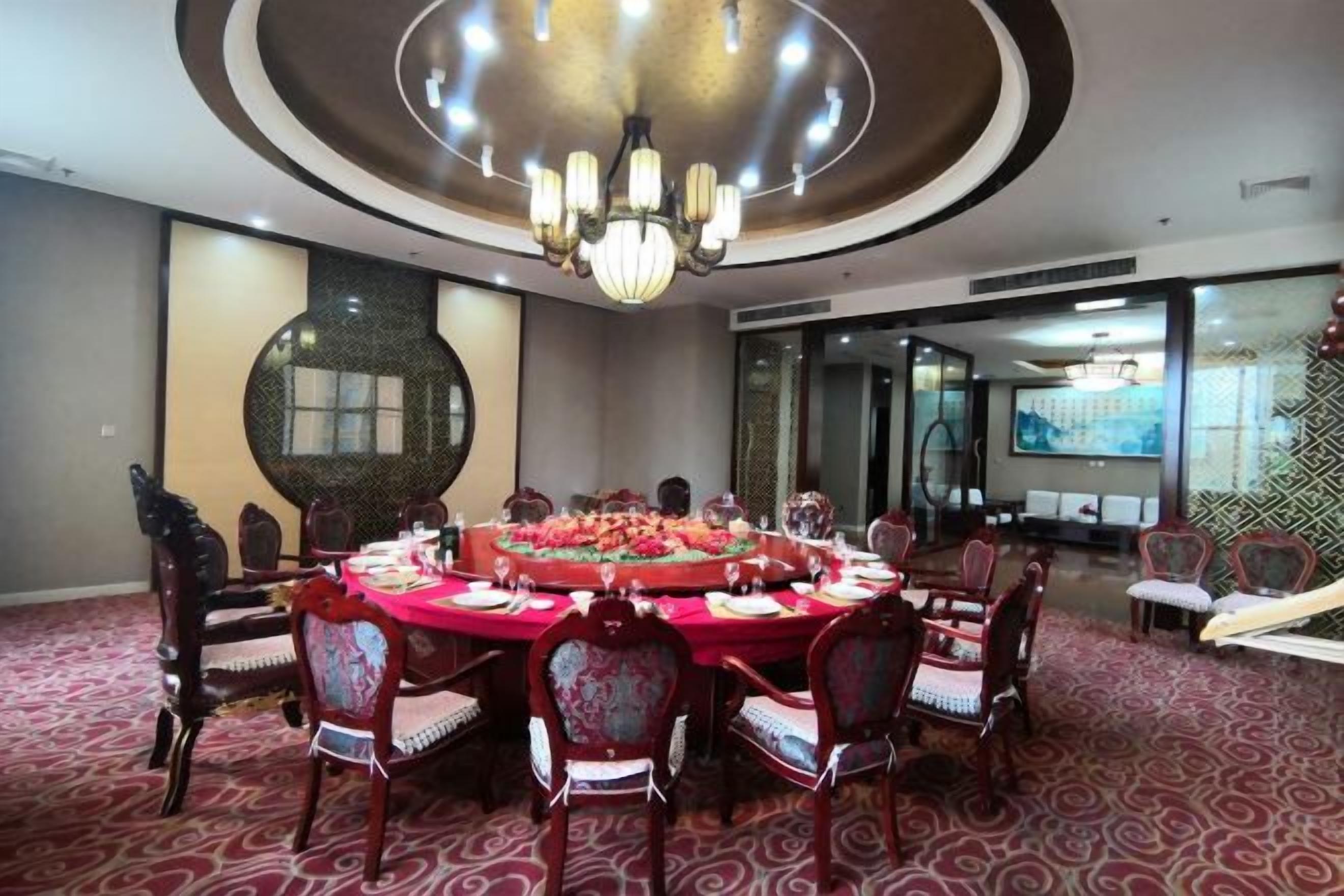 A conference room with a round table, chairs, and a chandelier.