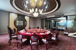 Un salón de conferencias con una mesa redonda, sillas y un candelabro.