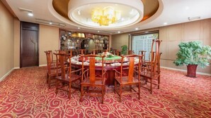A conference room with a round table, wooden chairs, a patterned carpet, and a chandelier.