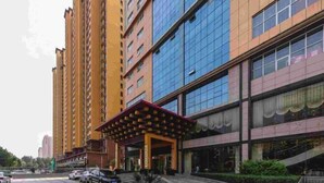 A multi-story hotel with a modern facade, a covered entrance, and a parking area.
