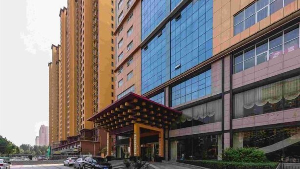 A multi-story hotel with a modern facade, a covered entrance, and a parking area.