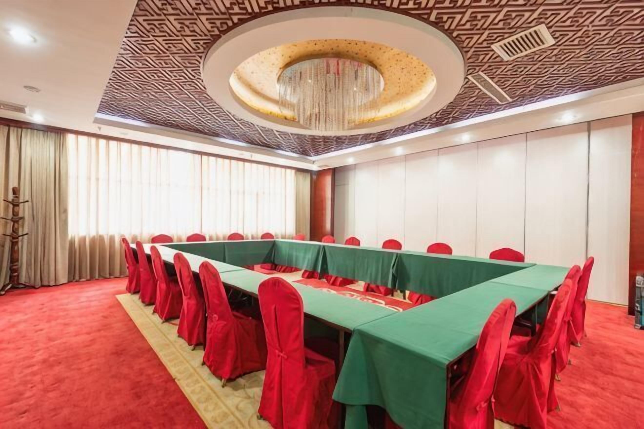A conference room with a long table, red chairs, and a patterned ceiling.