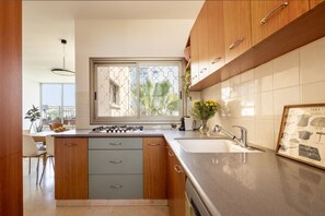 Een moderne keuken met een groot raam, houten kastjes, een ingebouwde kookplaat en een spoelbak.