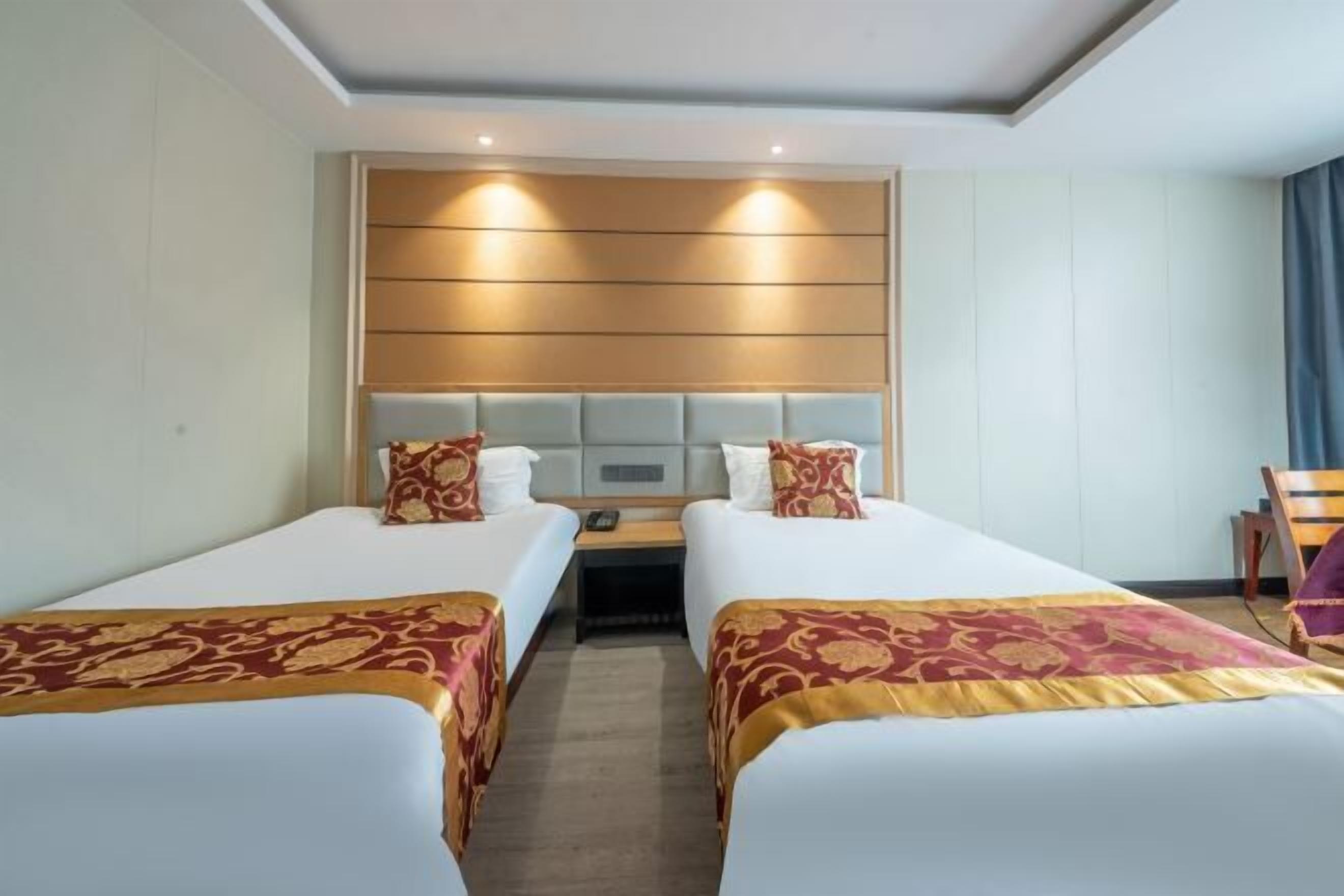 Ett hotellrum med två sängar, var och en med en sänggavel och nattduksbord.