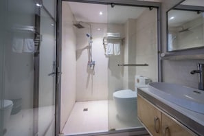 Un baño moderno con cabina de ducha de vidrio, inodoro y tocador con espejo.