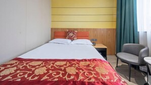 Une chambre d’hôtel avec un lit, une table de chevet, une chaise et une petite table.