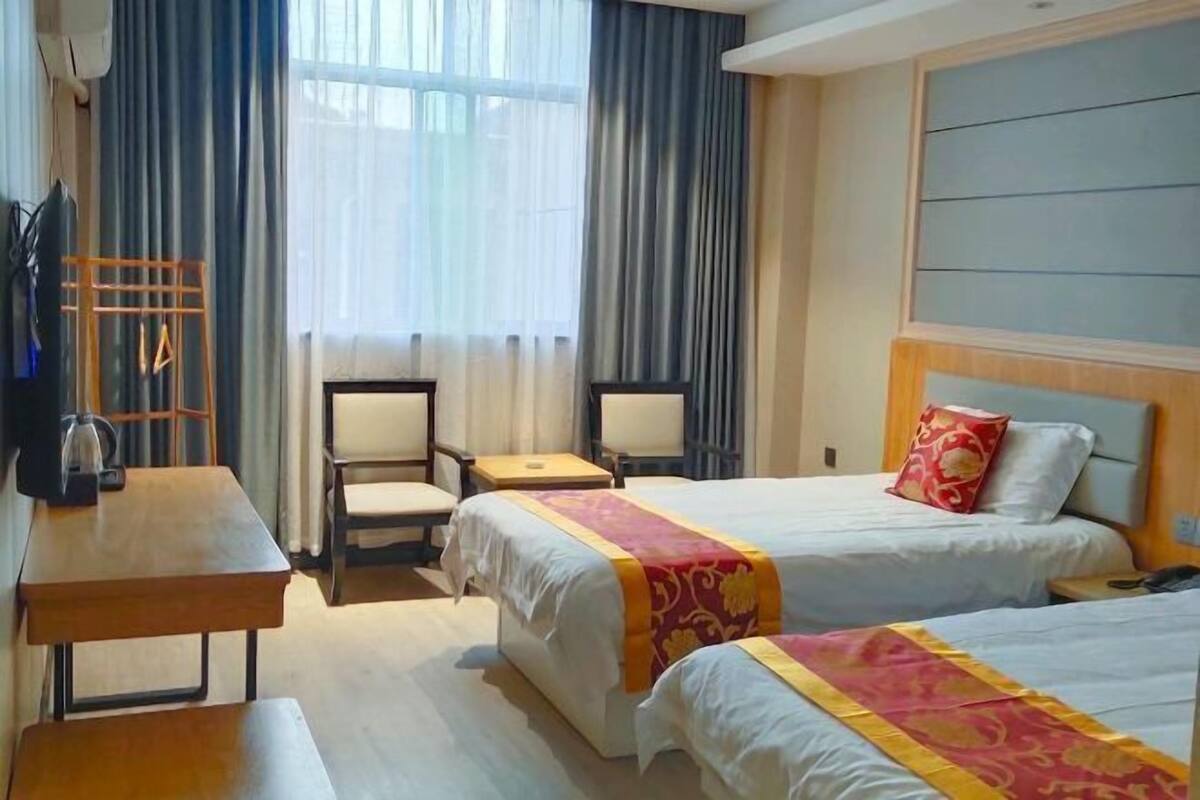 Une chambre d’hôtel avec deux lits, un bureau, une chaise et un téléviseur.