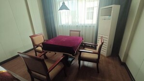 Une chambre d’hôtel comprenant une table à manger, quatre chaises, un lit, une fenêtre avec des rideaux et un radiateur mobile.