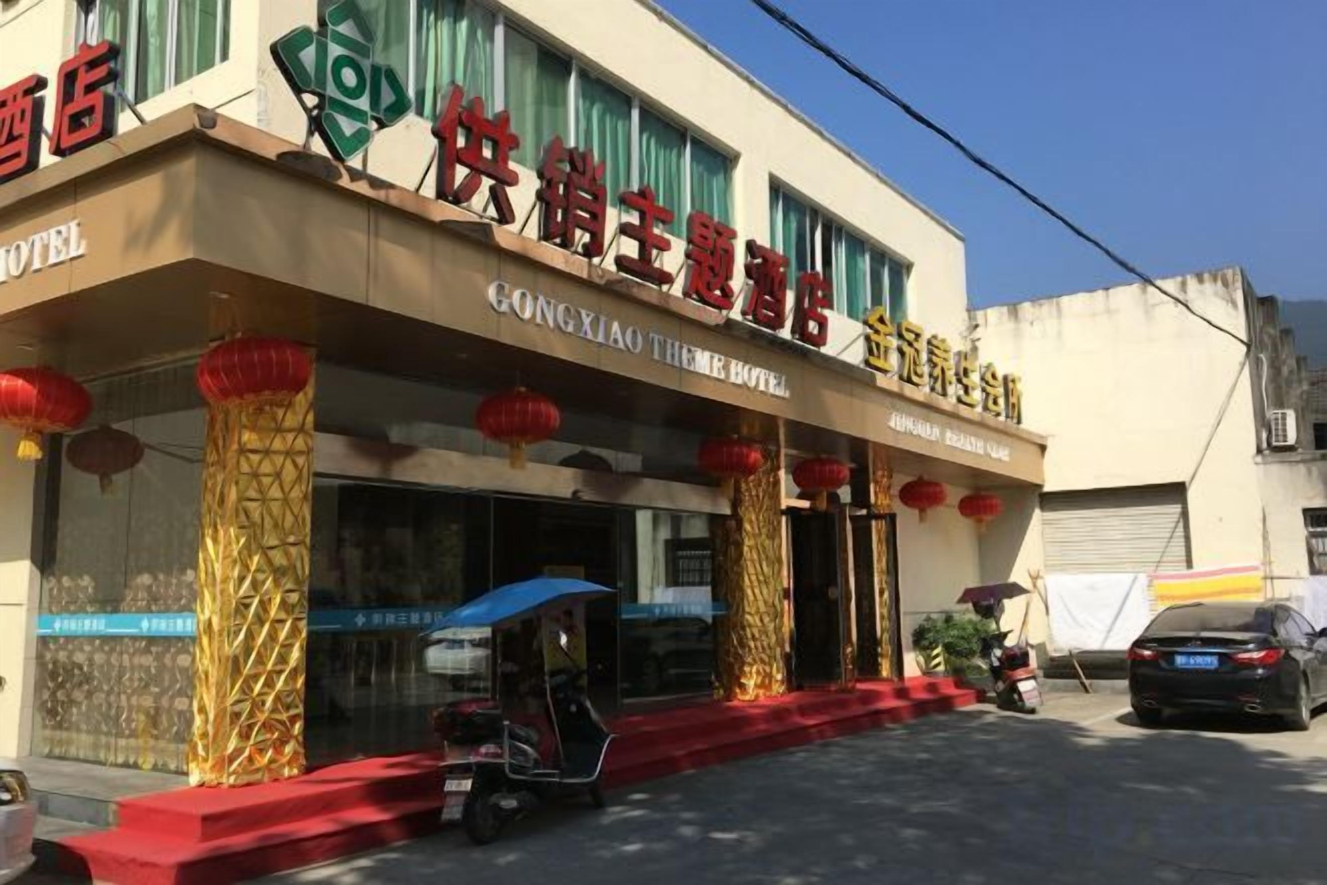 A hotel with a traditional architectural style, featuring a prominent entrance with red lanterns and golden pillars.