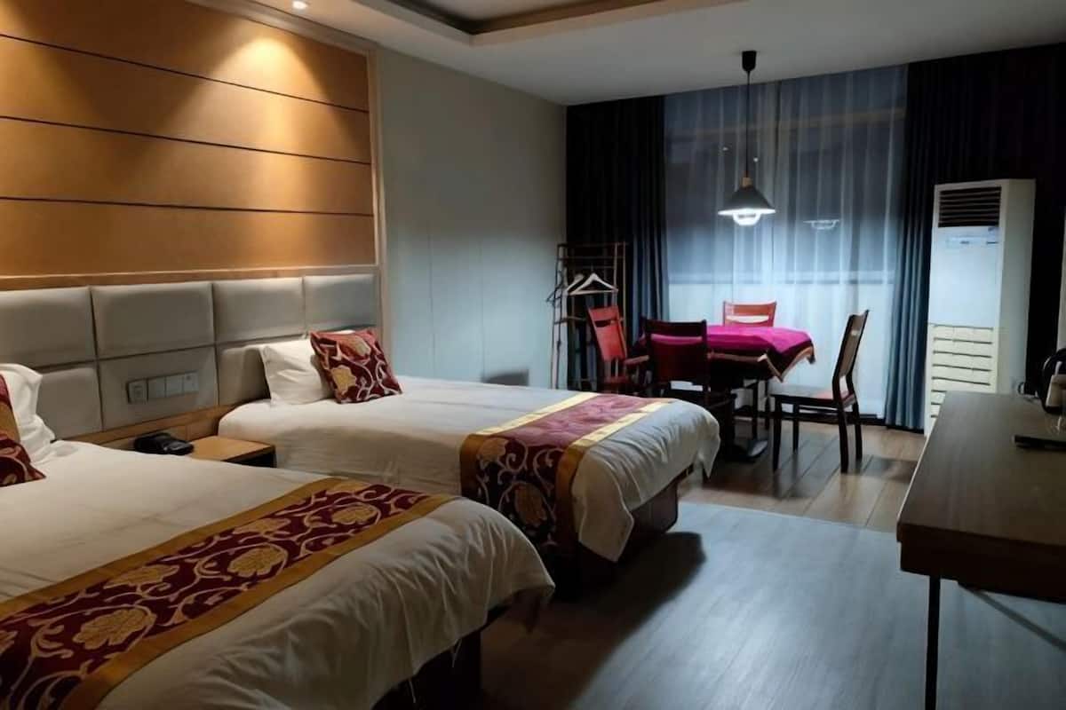 Une chambre d’hôtel avec deux lits, un bureau, une chaise et une table à manger.