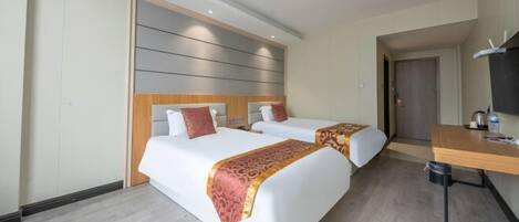 A hotel room with two beds, a wooden headboard, a desk with a chair, and a television.